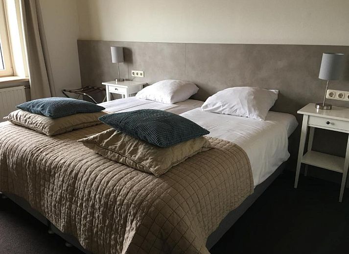Comfortabele slaapkamer in Hotel Posthuys Vlieland, Oost, met drie bedden op Waddeneilanden.