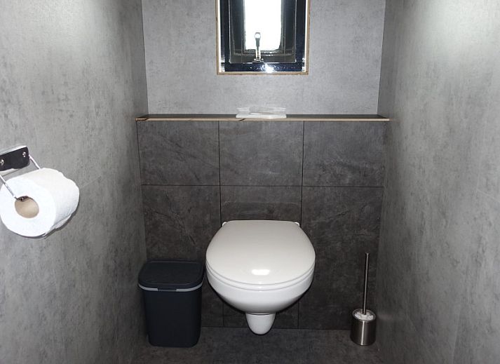 Dining area with large windows in Noorderlicht vacation home, Formerum, Terschelling, surrounded by greenery.