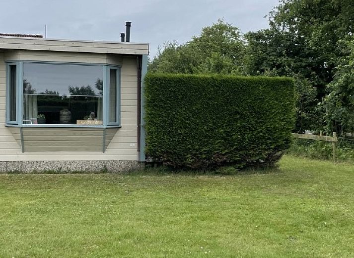 Cozy sitting area in chalet Klaver Vier in Formerum, Terschelling, with comfortable chairs and a view of the green surroundings.