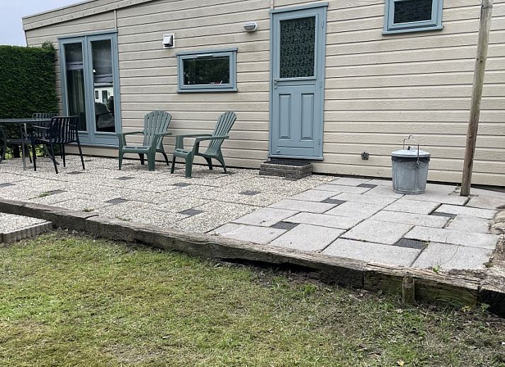 Cozy sitting area in chalet Klaver Vier in Formerum, Terschelling, with comfortable chairs and a view of the green surroundings.