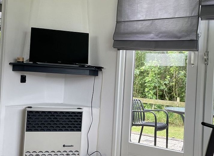 Cozy sitting area in chalet Klaver Vier in Formerum, Terschelling, with comfortable chairs and a view of the green surroundings.