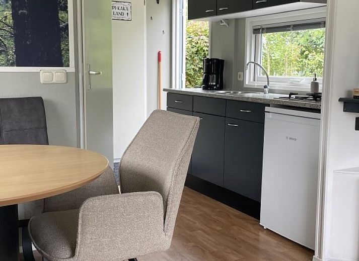 Cozy sitting area in chalet Klaver Vier in Formerum, Terschelling, with comfortable chairs and a view of the green surroundings.