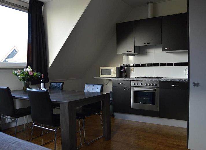 Moderne keuken in Wijnberg Appartementen, Hollum, Ameland met eettafel en apparatuur.