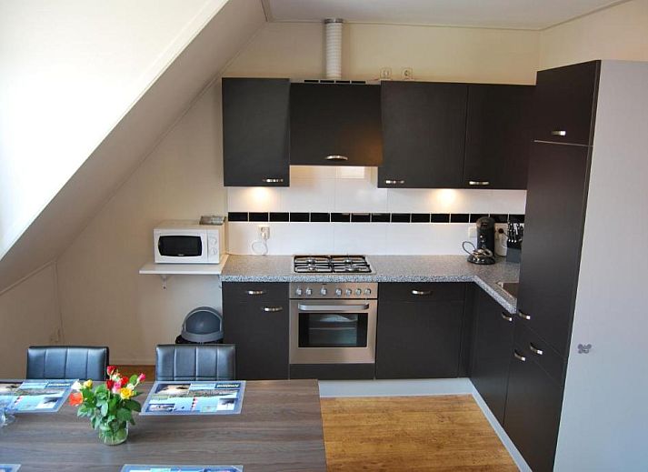 Gezellige eetruimte in Wijnberg Appartementen, Hollum, Ameland met keuken en tafel.