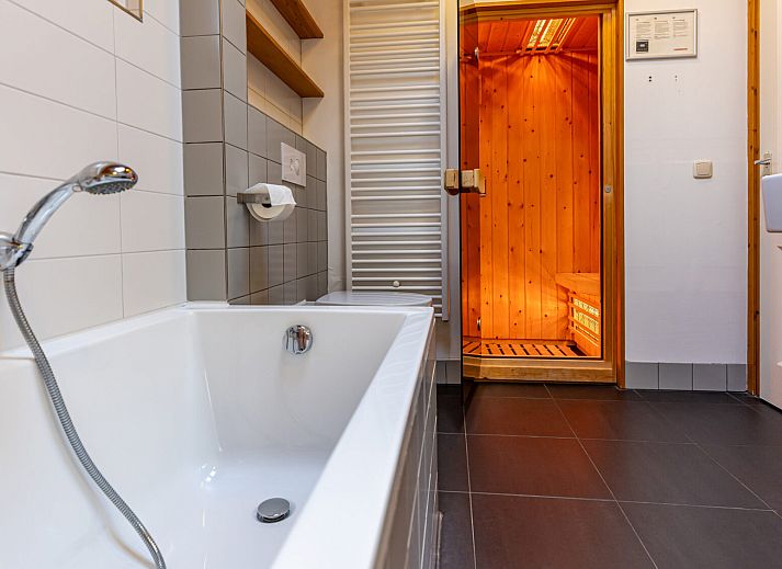 Knusse slaapkamer in Finse Bungalow infrarood sauna, Hee, Terschelling met houten wanden en uitzicht op de natuur.