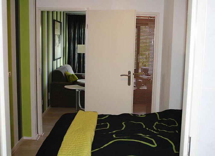 Terras van Appartement HELIOS - Amelander Kaap met ZWEMBAD in Hollum, Ameland, met kleurrijke stoelen en uitzicht op groen.