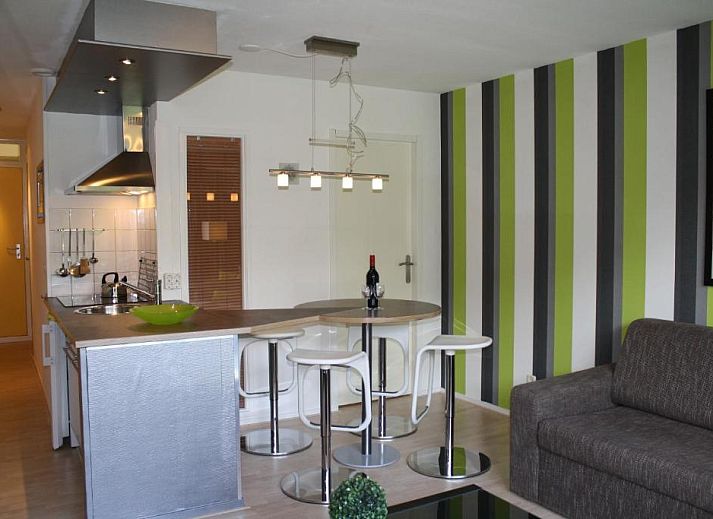 Terras van Appartement HELIOS - Amelander Kaap met ZWEMBAD in Hollum, Ameland, met kleurrijke stoelen en uitzicht op groen.