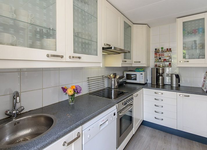 Gemuetliches Wohnzimmer von De Sjouw in Hoorn, Terschelling, mit geraeumiger Sitzecke und gemuetlichem Holzofen fuer einen entspannten Aufenthalt.