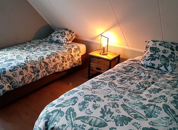 Gemuetlicher Innenraum in De Sjouw, Hoorn, Terschelling, mit bequemen Sofas und einem rustikalen Kamin fuer gemuetliche Abende.