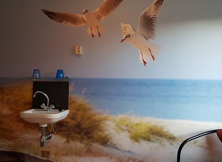 Gemuetlicher Innenraum in De Sjouw, Hoorn, Terschelling, mit bequemen Sofas und einem rustikalen Kamin fuer gemuetliche Abende.