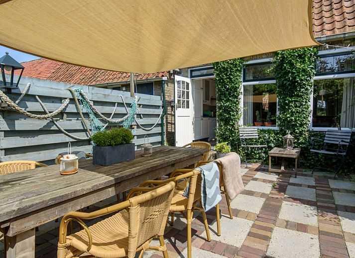 Esszimmer in De Sjouw, Hoorn, Terschelling, mit Holztisch und Buecherregal, ideal fuer Familienessen und Lesestunden.