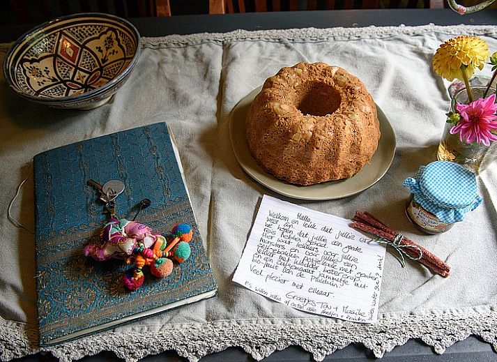 Esszimmer in De Sjouw, Hoorn, Terschelling, mit Holztisch und Buecherregal, ideal fuer Familienessen und Lesestunden.