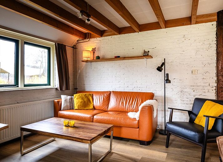 Cozy living room of apartment Kip 2 in Hoorn, Terschelling with wooden beams and comfortable seating area.