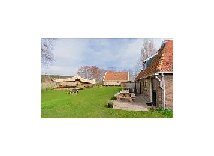 Atmospheric terrace at Kip 2 in Hoorn, Terschelling with evening lighting and a cozy outdoor fireplace.
