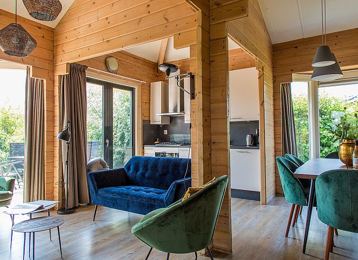 Gezellig terras met blauwe parasol bij Villabungalow, vakantiehuis in Oosterend, Terschelling, omringd door groene hagen op de Waddeneilanden.