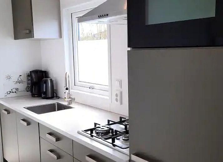 Buitenkant van WadRust chalet in Midsland Noord, Terschelling met houten gevel en zonnebloemen.