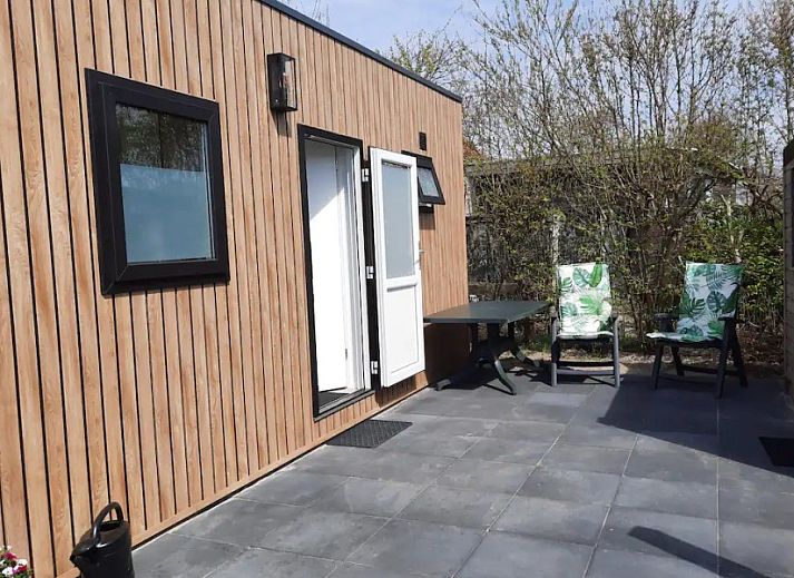 Buitenkant van WadRust chalet in Midsland Noord, Terschelling met houten gevel en zonnebloemen.