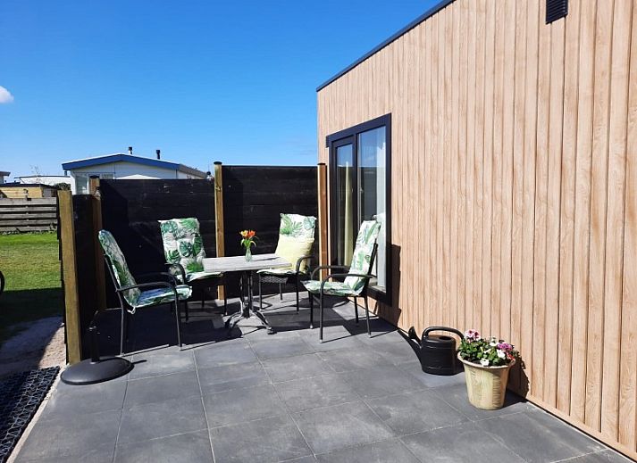 Comfortabele zithoek in WadRust chalet, Midsland Noord, Terschelling met grote ramen en lichte bank.