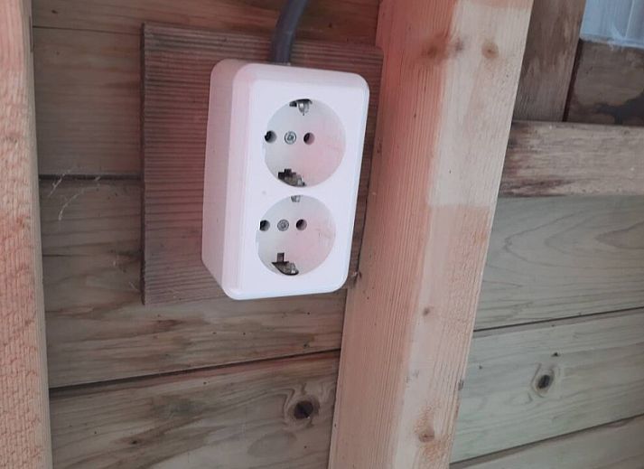 Comfortabele zithoek in WadRust chalet, Midsland Noord, Terschelling met grote ramen en lichte bank.