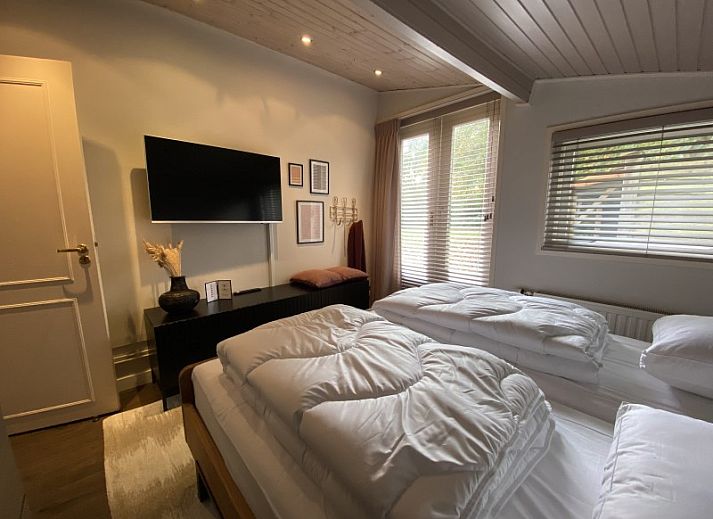 Gemuetlicher Innenbereich des Ferienhauses Belhamel in Midsland Noord, Terschelling mit bequemen Sitzgelegenheiten und grossen Fenstern.