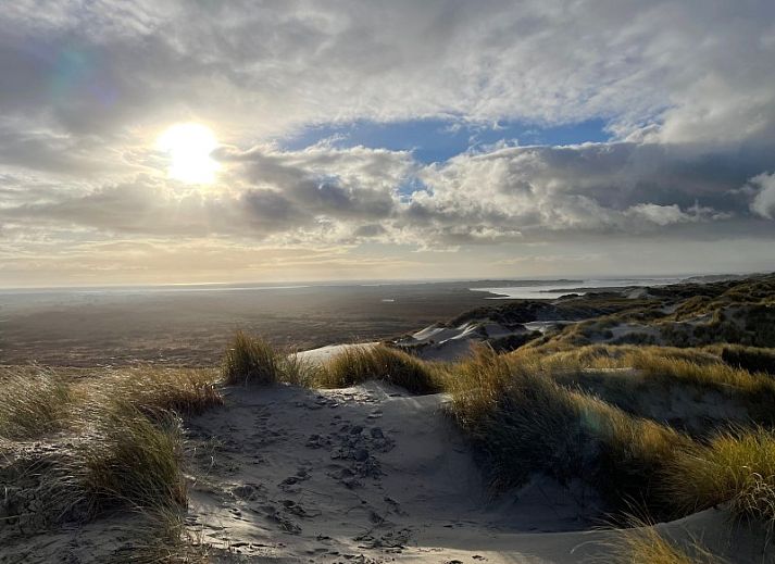 Gemuetliches Wohnzimmer des Duinhuis in Midsland Noord, Terschelling, mit bequemen Sofas und Blick auf die Natur fuer einen gemuetlichen Urlaub.