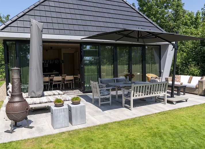 Noordhoek vakantiehuis in Midsland Noord, Terschelling omgeven door weelderige natuur en groene tuin, ideale plek voor ontspanning.