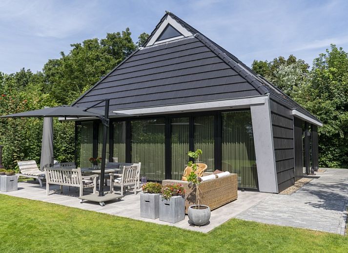 Noordhoek vakantiehuis in Midsland Noord, Terschelling omgeven door weelderige natuur en groene tuin, ideale plek voor ontspanning.