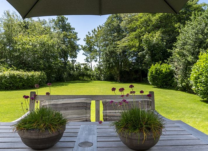 Noordhoek vakantiehuis in Midsland Noord, Terschelling omgeven door weelderige natuur en groene tuin, ideale plek voor ontspanning.