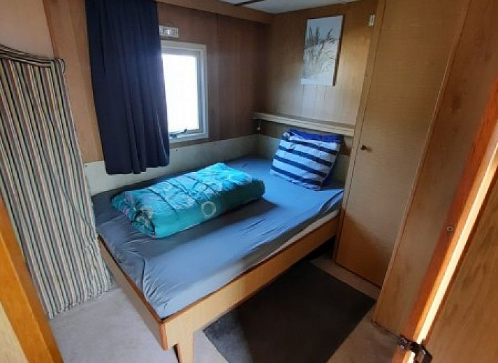 Gezellige slaapkamer in chalet De Albatros, West-Terschelling, met knus bed en houten interieur, ideaal voor een ontspannen verblijf op Terschelling.