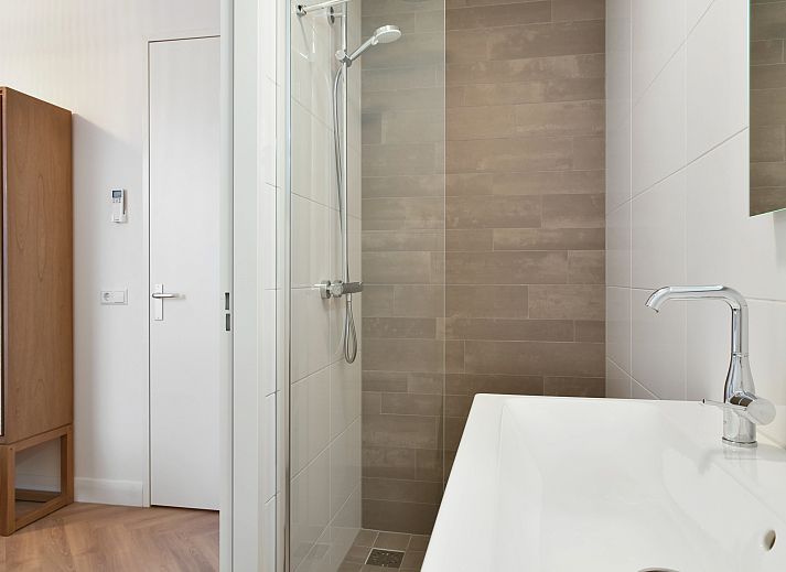 Lichte woonkamer van 4-persoons penthouse 4CP in West-Terschelling, met comfortabele zithoek en uitzicht op de duinen.