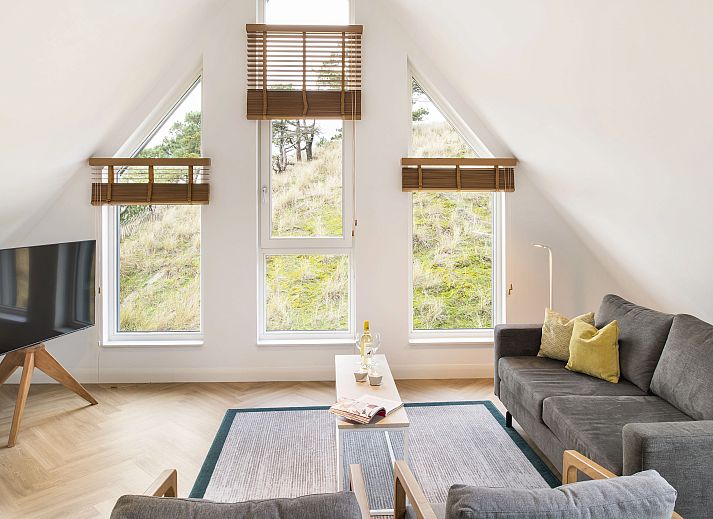 Lichte woonkamer van 4-persoons penthouse 4CP in West-Terschelling, met comfortabele zithoek en uitzicht op de duinen.