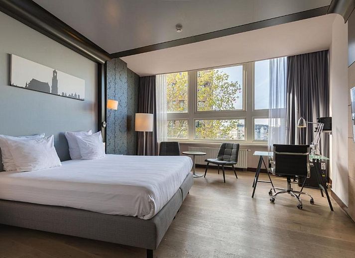 Luxe slaapkamer in Apollo Hotel Utrecht City Centre met balkon en uitzicht op Utrecht, ideaal voor een ontspannen verblijf.