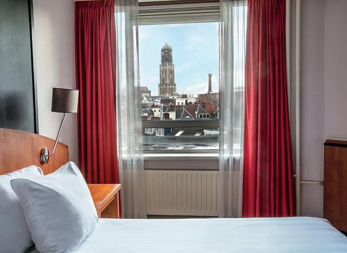 Luxe slaapkamer in Apollo Hotel Utrecht City Centre met balkon en uitzicht op Utrecht, ideaal voor een ontspannen verblijf.