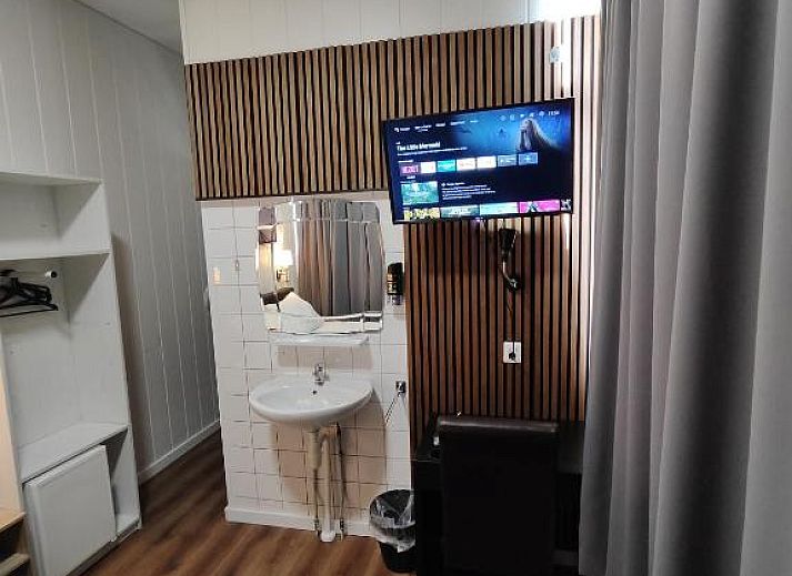 Stijlvolle televisiehoek in Hotel Holland Lodge, Utrecht met moderne faciliteiten.