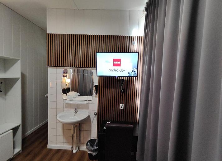 Stijlvolle televisiehoek in Hotel Holland Lodge, Utrecht met moderne faciliteiten.