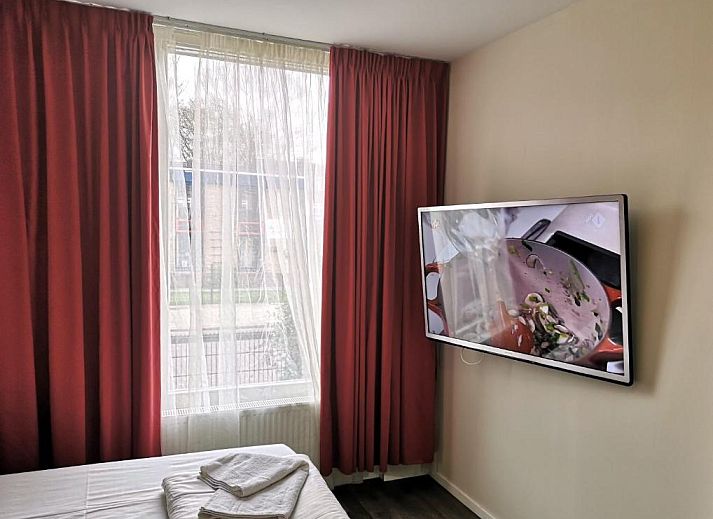 Gezellige slaapkamer in Hotel Holland Lodge Utrecht met uitzicht op de stad.