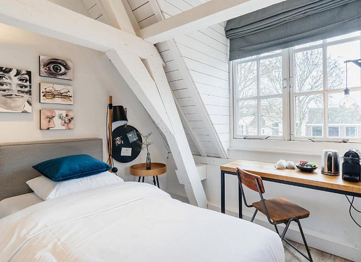 Sfeervolle slaapkamer in Eye Hotel Utrecht met kunst aan de muur en groot raam met uitzicht.