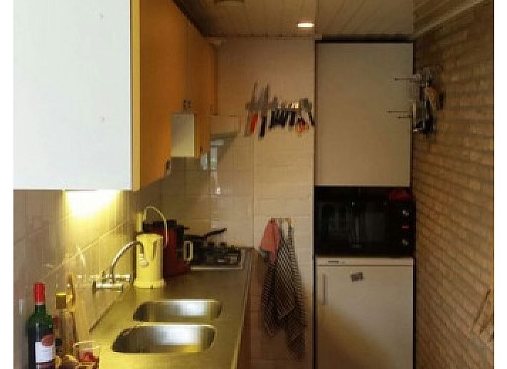 Cozy living room in Jans vacation home, Ballum, Ameland, with fireplace and wooden beams.