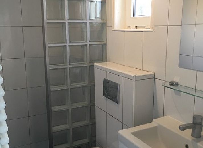 Ruim terras van Estrella in Ballum, Ameland met kleurrijke stoelen en groene tuin op de Waddeneilanden.