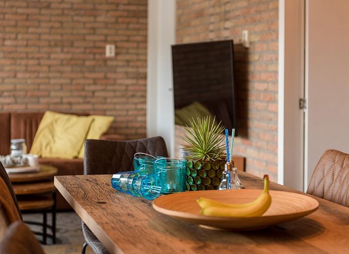 Gezellig terras bij Artemis vakantiehuis in Ballum, Ameland met comfortabele loungebanken en parasol.