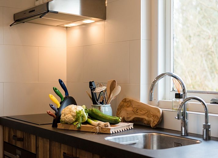 Gezellig terras bij Artemis vakantiehuis in Ballum, Ameland met comfortabele loungebanken en parasol.