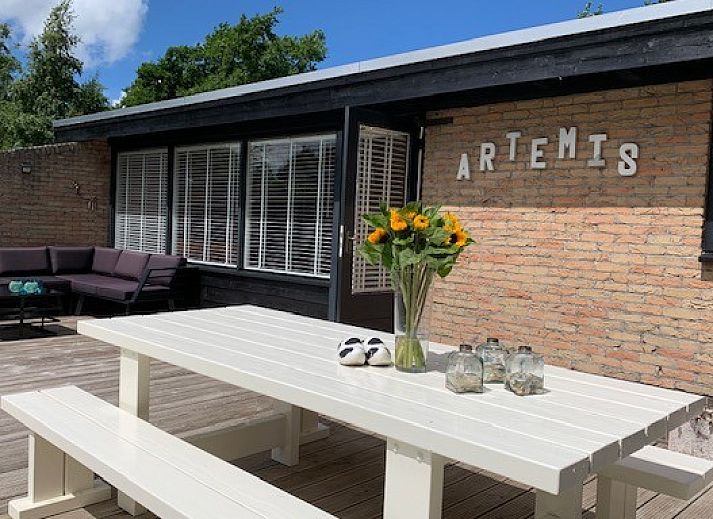 Detail van het terras bij Artemis vakantiehuis in Ballum, Ameland met een vaas zonnebloemen en decoratieve elementen.