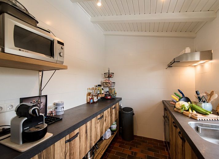 Detail van het terras bij Artemis vakantiehuis in Ballum, Ameland met een vaas zonnebloemen en decoratieve elementen.