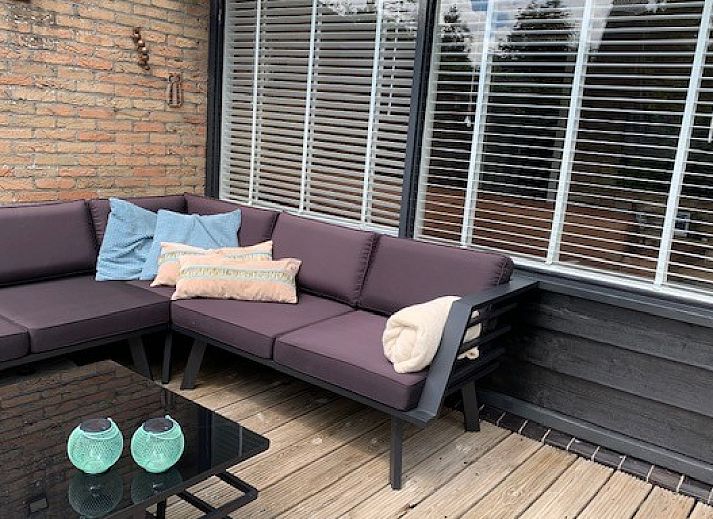 Sfeervolle woonkamer van vakantiehuis Artemis in Ballum, Ameland met een hoekbank en veel natuurlijk licht.