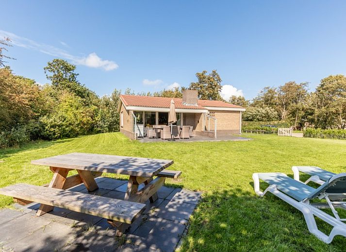 Ferienhaus Duinroos in Ballum, Ameland, umgeben von viel Gruen, einer grossen Wiese und blauem Himmel.