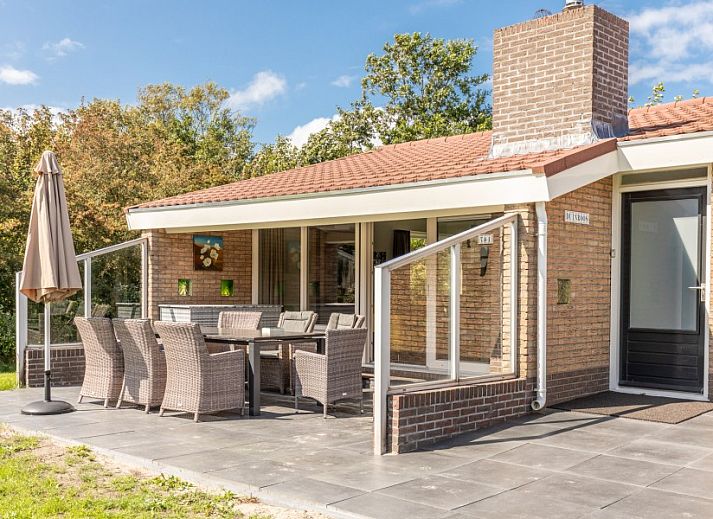 Ferienhaus Duinroos in Ballum, Ameland, umgeben von viel Gruen, einer grossen Wiese und blauem Himmel.