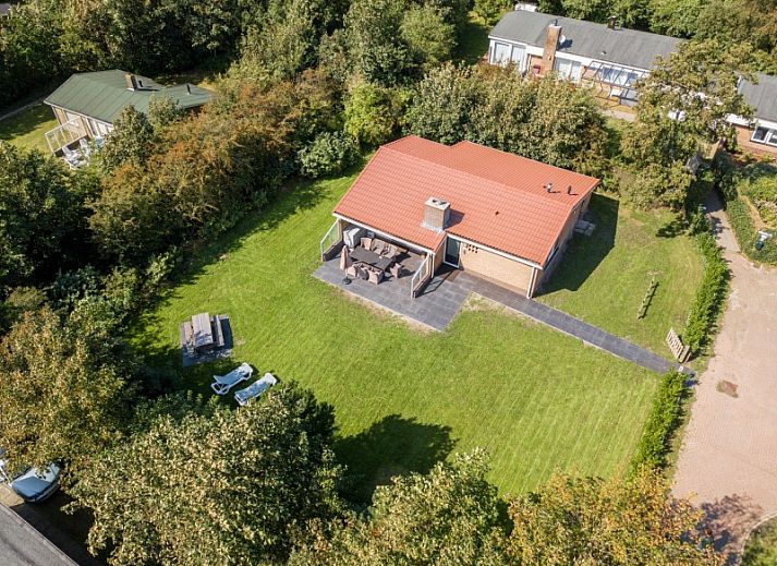 Ferienhaus Duinroos in Ballum, Ameland, umgeben von viel Gruen, einer grossen Wiese und blauem Himmel.