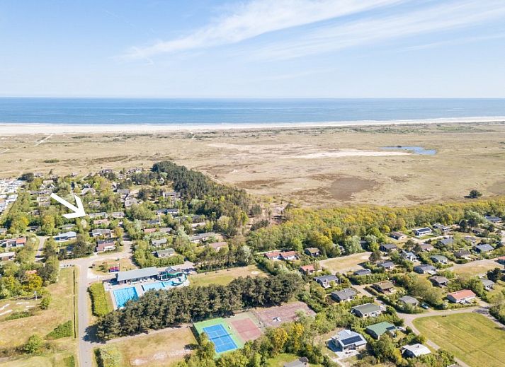 Ferienhaus Duinroos in Ballum, Ameland, umgeben von viel Gruen, einer grossen Wiese und blauem Himmel.