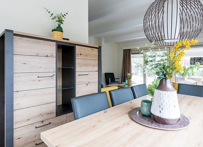 Gemuetlicher Aussenbereich des Ferienhauses Duinroos, Ballum, Ameland, mit Terrassenmoebeln unter einem Sonnenschirm.