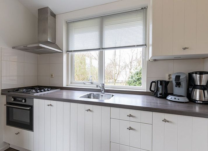 Gemuetlicher Aussenbereich des Ferienhauses Duinroos, Ballum, Ameland, mit Terrassenmoebeln unter einem Sonnenschirm.